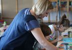 Kobieta pomaga dzieciom malować