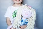 Uśmiechnięta dziewczynka trzyma szmacianą lalkę