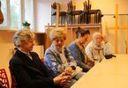 Seniorzy siedzą za stołem i rozmawiają