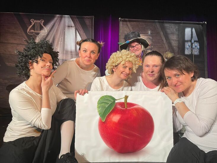 Aktorzy zgromadzeni wokół obrazu z jabłkiem
