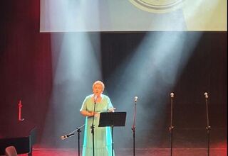 Seniorka w zielonej sukni śpiewa na scenie