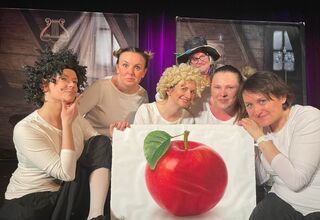 Aktorzy na scenie z obrazem przedstawiającym jabłko