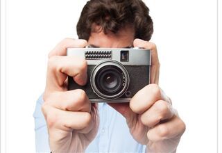 Plakat przedstawiający mężczyznę, który ma przed sobą aparat i robi zdjęcie