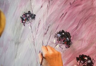 Obraz w różowej kolorystyce z czarnymi zarysami polnych kwiatów, który kończy uczestniczka zajęć domalowując kolejne fragmenty