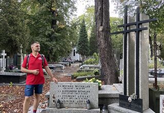 Mężczyzna w czerwonej koszulce przy grobie Zygmunta Jórskiego