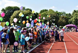 Dzieci i młodzież z balonami na stadionie lekkoakteltycznym