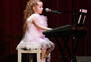 Dziewczynka w białej sukience grająca na pianinie
