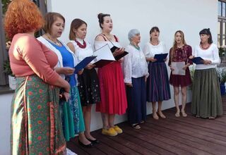 Grupa kobiet śpiewająca na drewnianym podeście