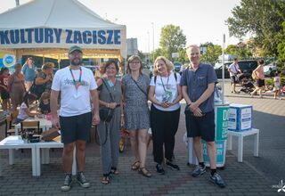 Uśmiechnięci kobiety i mężczyźni, w tle namiot Dom Kultury Zacisze