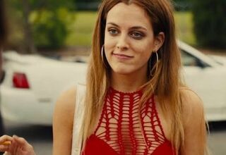 Zdjęcie: kadr z filmu American Honey, nastolatka w długich włosach, w skąpej bluzce, w tle stare auto
