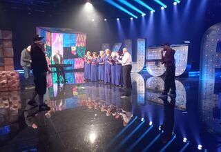 Zdjęcie: Seniorki  w niebieskich sukienkach i seniorzy podczas próby przed występem