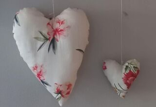Zdjęcie dwóch białych materiałowych serduszek z elementami różowych kwiatów