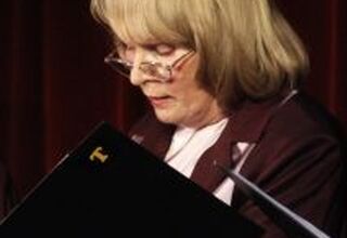 Zdjęcie kobiety w średnim wieku trzymającej teczkę z nutami