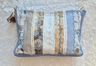 Zdjęcie: kosmetyczka w pastelowej tonacji z przewagą niebieskiego z pasków materiałów łączonych koronką na jasnym tle