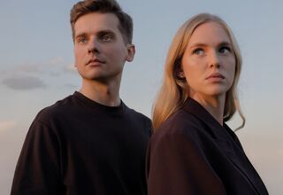 Zdjęcie: młoda kobieta w blond włosach i młody mężczyzna, wpatrzeni w ten sam kierunek, nad nimi jasne niebo