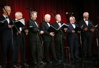 Zdjęcie mężczyzn w ciemnych garniturach na scenie