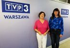 Dyrektor Domu Kultury Zacisze pozuje do zdjęcia z kobietą na tle loga TVP 3 Warszawa