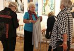 Grupa kobiet stoi w sali z wystawą obrazów