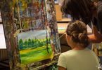 Kobieta pomaga dziewczynce malować pejzaż
