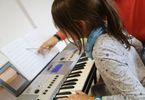 Mężczyzna uczy dziewczynkę gry na keyboardzie
