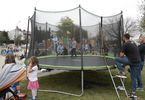 Dzieci bawią się na trampolinie. Obok stoją dorośli.