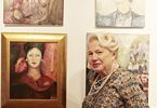 Kobieta pozuje na tle wystawy portretów