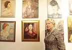 Kobieta pozuje na tle wystawy portretów