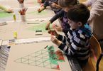 Dzieci malują rysunki choinek wykonane z trójkątów
