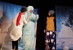 Kobieta przebrana za bałwanka i kobieta w stroju zimowym występują na scenie. Miedzy nimi stoi mężczyzna przebrany za yeti.