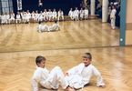 Dwóch chłopców ćwiczyć karate. W lustrze odbija się grupa dzieci.
