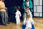 Mężczyzna w stroju do karate pasuje dziewczynkę na ucznia