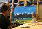 Dziecko maluje pejzaż przedstawiający góry