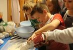 Dzieci wysypują mąkę na plastikową tacę