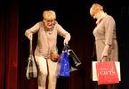 Dwie kobiety występują na scenie i niosą torby na zakupy