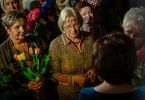 Kobieta wręcza kwiaty dyrektor Bożennie Dydek. Obok stoi grupa osób.