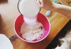 Dziecko wsypuje cukier do miski z mąką