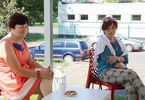Dwie kobiety siedzą na podwórku przy stolikach