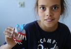 Dziewczynka trzyma zabawkę wykonaną z plastikowego pudełeczka i plasteliny
