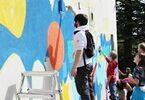 Grupa nastolatków maluje mural na ścianie