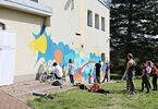 Grupa osób maluje mural na ścienie budynku Domu Kultury Zacisze