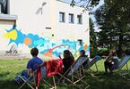 Grupa nastolatków siedzi na leżakch i przygląda się graffiti