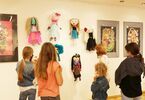 Grupa dziewczynek ogląda wystawę ręcznie wykonanych, materiałowych lalek