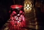 Dwa lampiony ozdobione makramą, z zapalonymi świeczkami w środku
