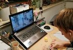 Chłopak tworzący swoje roślinne dzieło. Przed nim znajduje się laptop z filmikiem instruktażowym.