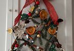 Gwiazda betlejemska ozdobiona kokardą, suszoną pomarańczą oraz sztucznymi świątecznymi dekoracjami