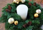 Stroik świąteczny ozdobiony bombkami i szyszek, ze świeczką w środku