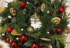 Wianek bożonarodzeniowy udekorowany małymi bombkami, sztucznymi owocami oraz szyszkami