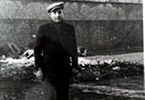Leon Wanat w ubraniu cywilnym przy murze Pawiaka. Zdjęcie czarno-białe.