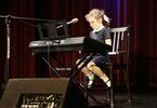 Dziewczynka w stroju galowym gra na keyboardzie.