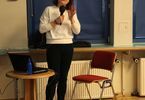 Magda Bialic ubrana w czarne spodnie i białą bluzkę stoi na tle okna w sali wykładowej
